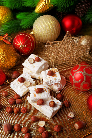 Sweet nougat with hazelnuts and Christmas decoration table close upの写真素材
