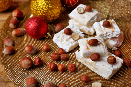 Sweet nougat with hazelnuts and Christmas decoration table close upの写真素材