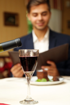 Young attractive man at the restaurant. Focus on wine glassの写真素材