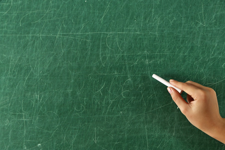 Female hand writing on blackboard with chalk, close upの写真素材