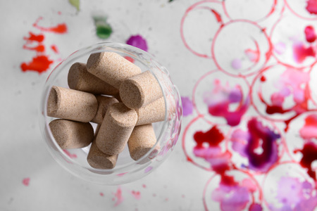 Wineglass full of corks and grapes painted with wine and watercolors on paper backgroundの写真素材