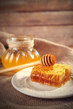 Pot of honey and honeycomb with dipper on wooden tableの写真素材