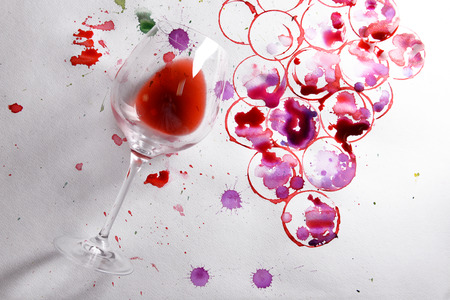 Wineglass of spilled wine with watercolors stains on paper backgroundの写真素材