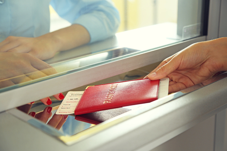 Woman buying tickets with passport at box officeの写真素材