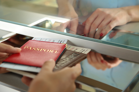 Woman buying tickets with passports at box officeの写真素材