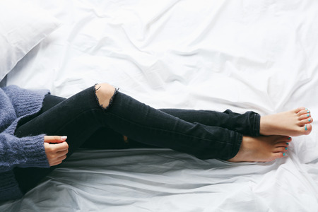 Woman in black jeans on bed top view point