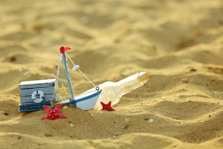 A little yacht with bottle and chest on the seashoreの写真素材