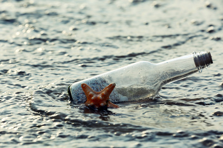 Bottle with starfish on sandy beachの写真素材