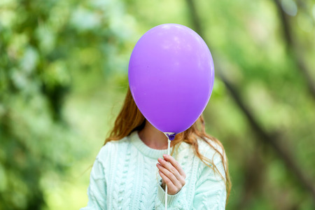 Girl holding balloon near faceの写真素材