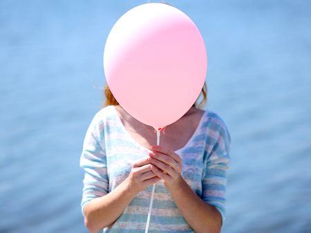 Girl holding balloon near faceの写真素材