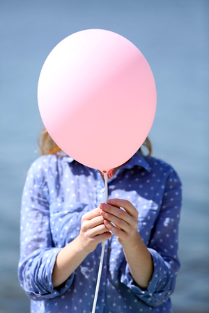 Girl holding balloon near faceの写真素材