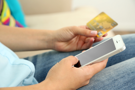 Female's hands hold credit card and cellphone, close upの写真素材