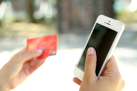 Cellphone and credit card in woman's hands outdoors, close upの写真素材