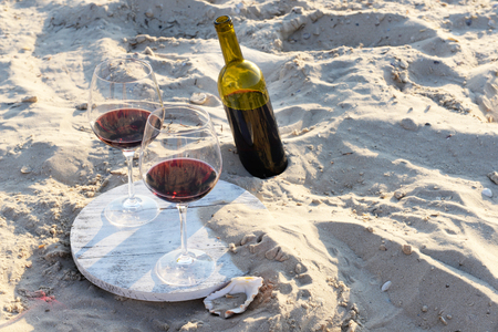 Wine bottle and glasses on sand backgroundの写真素材
