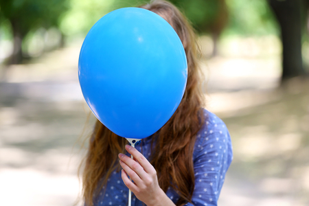 Girl holding balloon near faceの写真素材