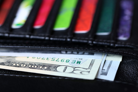 Black leather wallet with colourful credit cards and money, close upの写真素材