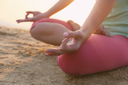 Young beautiful woman meditating yoga on the beach, close upの写真素材