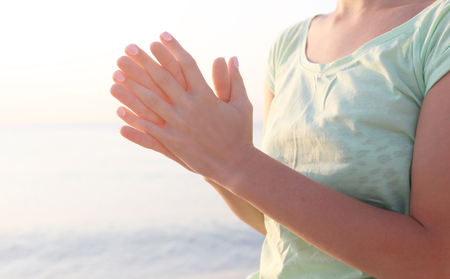 Young beautiful woman meditating yoga on the beach, back view, close upの写真素材
