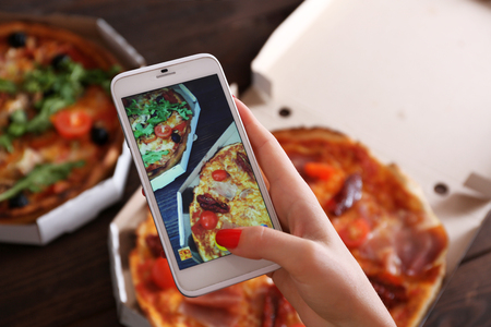 Woman taking a photo of pizza with the smartphoneの写真素材