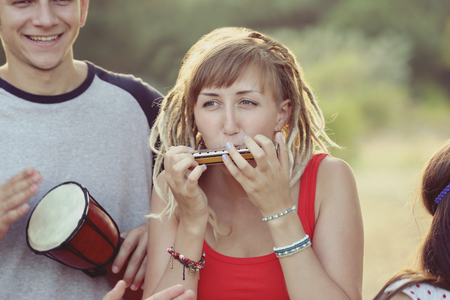 A girl with dreadlocks and harmonica in the forest outdoorsの写真素材