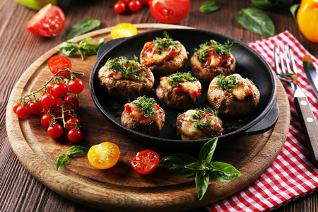 A frying pan with stuffed mushrooms and vegetables on the tableの写真素材