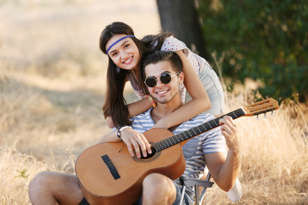 Attractive couple playing guitar, outdoorsの写真素材
