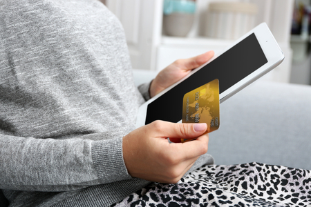 Concept for Internet shopping: woman with digital tablet and credit card sitting on sofa, at homeの写真素材