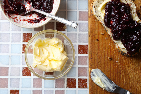 Tasty jam on the plate, butter, fresh bread and wooden tablet on mosaic backgroundの写真素材