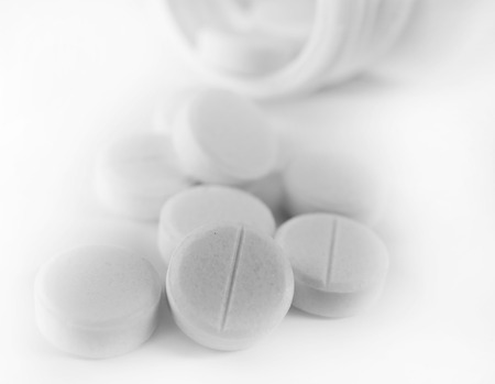 Blue drugs spilled from pill bottle on white background, close upの写真素材