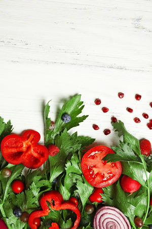 Cute bouquet of parsley and dill decorated with tomatoes, pepper and berries on light wooden background, close upの写真素材