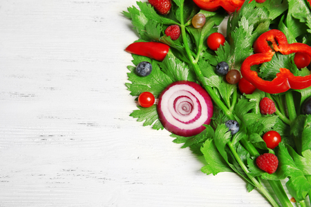 Cute bouquet of parsley and dill decorated with tomatoes, pepper and berries on light wooden background, close upの写真素材