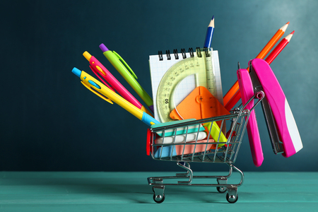 Bright stationery objects in mini supermarket cart on chalkboard backgroundの写真素材