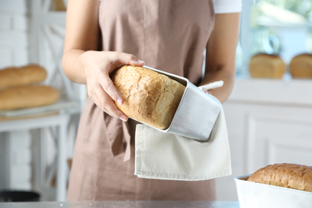 Baker with freshly baked bread in kitchen of bakeryの写真素材