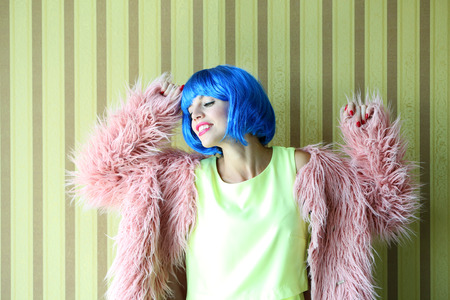 Young woman with blue hairstyle on stripped wall backgroundの写真素材
