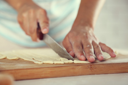 Woman making apple pie on wooden table, on light background