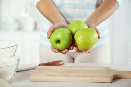 Female hands with fresh apples for pie, close-up, on light backgroundの写真素材