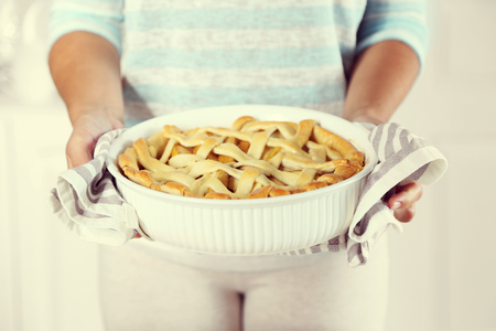 Homemade apple pie  in female hands, on light backgroundの写真素材