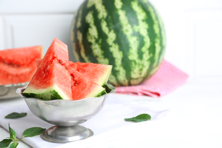 Sliced watermelon in metal bowl on white tableの写真素材