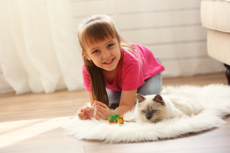 Little cute girl playing with kitten at homeの写真素材