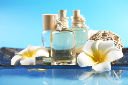 Beautiful composition of aroma oil and flowers on water against blue backgroundの写真素材