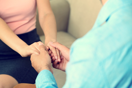 Concept of support - man and woman holding hands in the roomの写真素材