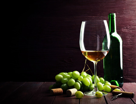 Bottle and glass of wine with grape on wooden backgroundの写真素材