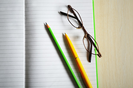 Opened striped note book with stationery on wooden background, close upの写真素材