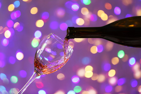 Wine pouring in glass on bright backgroundの写真素材