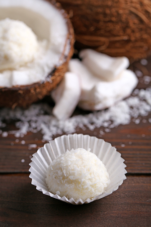 Candies in coconut flakes and fresh coconut on dark wooden backgroundの写真素材