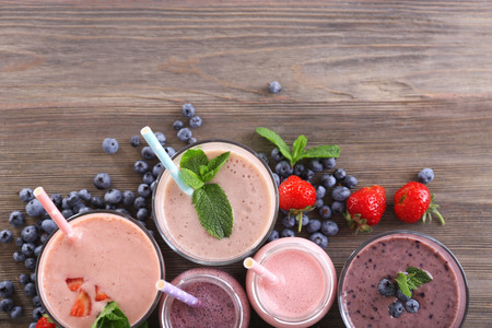 Berry yogurts in a row decorated with berries and mint on wooden background, empty spaceの写真素材