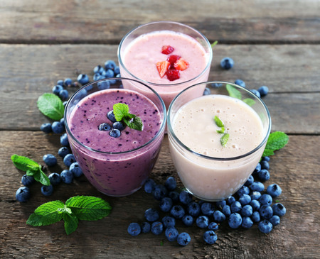 Tasty blueberry, strawberry and milk yogurts with berries and mint around on wooden backgroundの写真素材