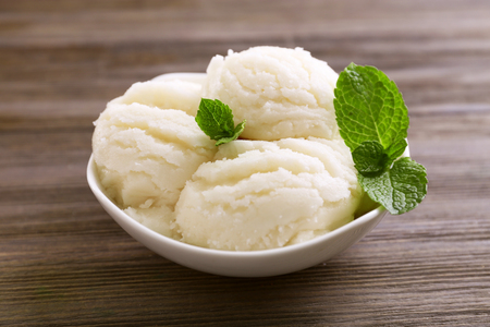 Vanilla ice-cream in a bowl decorated with mint on wooden backgroundの写真素材