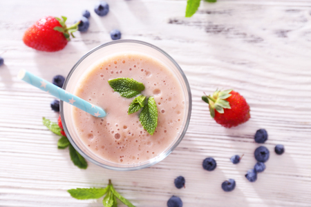 Fresh strawberry yogurt with berries around on light wooden backgroundの写真素材