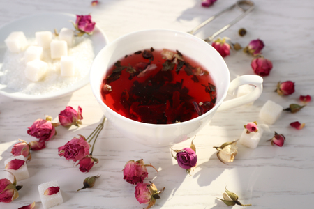 Tea and tea rose flowers on table closeupの写真素材
